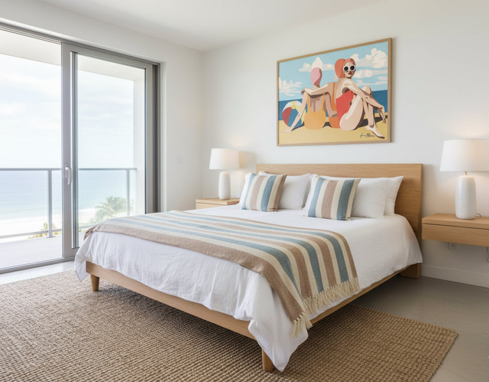 Three women in swimsuits sitting on a beach with a colourful ball and blue sky. Retro pop art print. Framed on a coastal house bedroom wall.