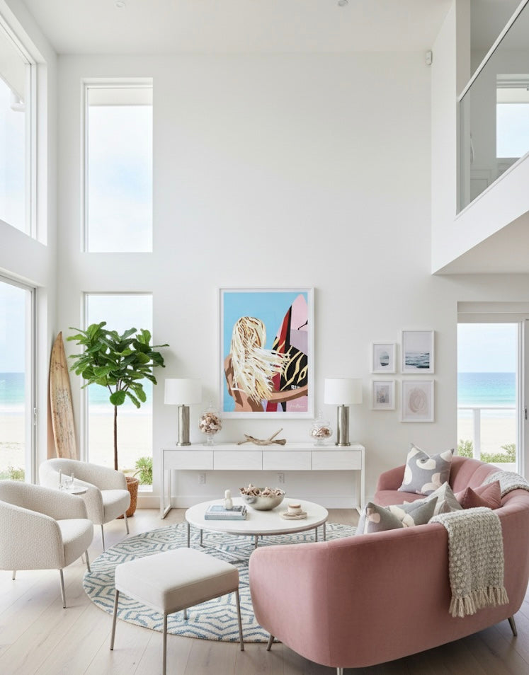 Framed art print of a woman with long blonde hair holding a colourful surfboard against a blue background a gallery on a white wall in a coastal living room.