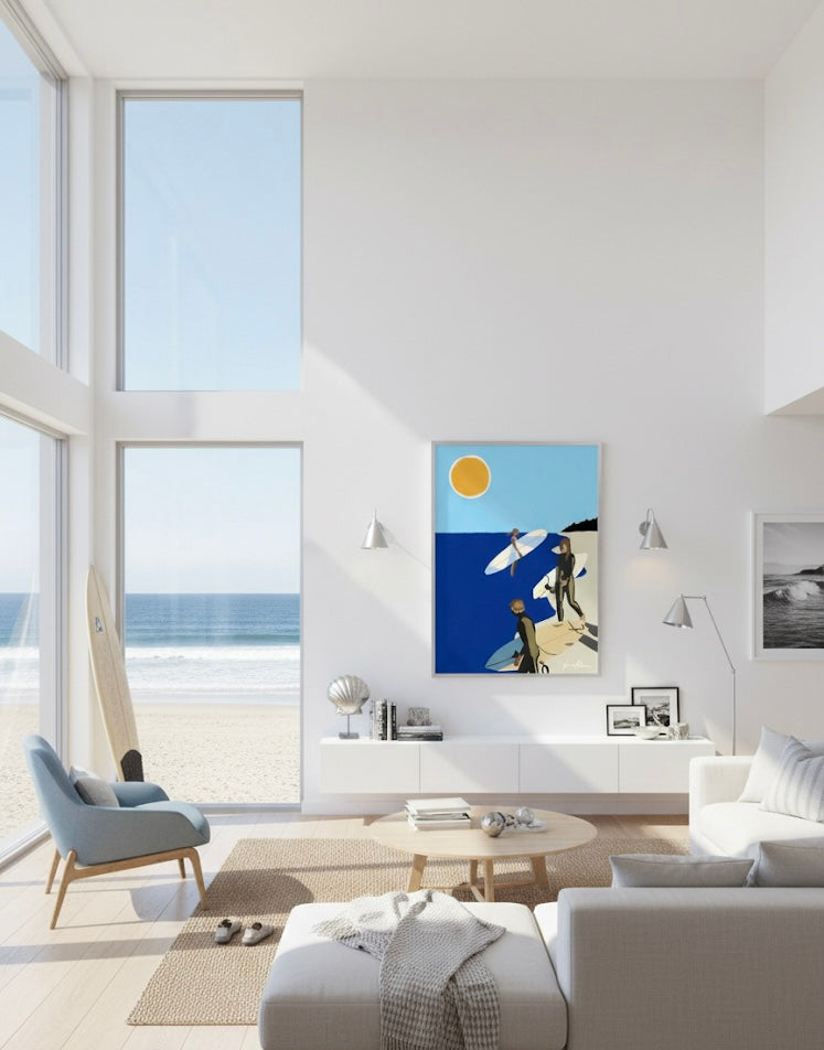 Framed art print of three surfers with surfboards on a beach under a bright sun. On a beach house living room wall.