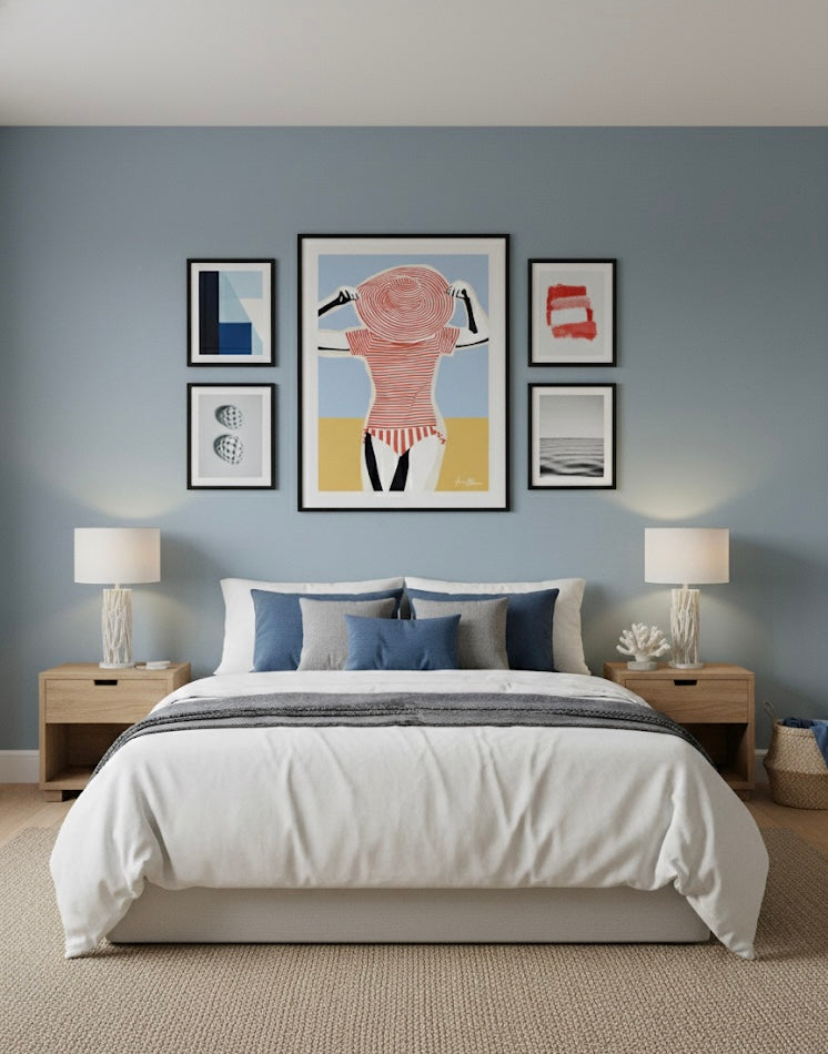 A gallery including an art print Illustration of a woman wearing a red and white striped swimsuit with a matching large hat against a blue sky and sand background on a bedroom wall.