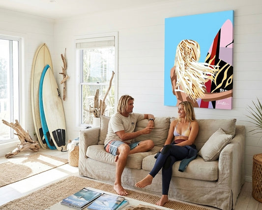Surf girl canvas art hanging in a coastal beach house with a surfer couple relaxing on the couch.