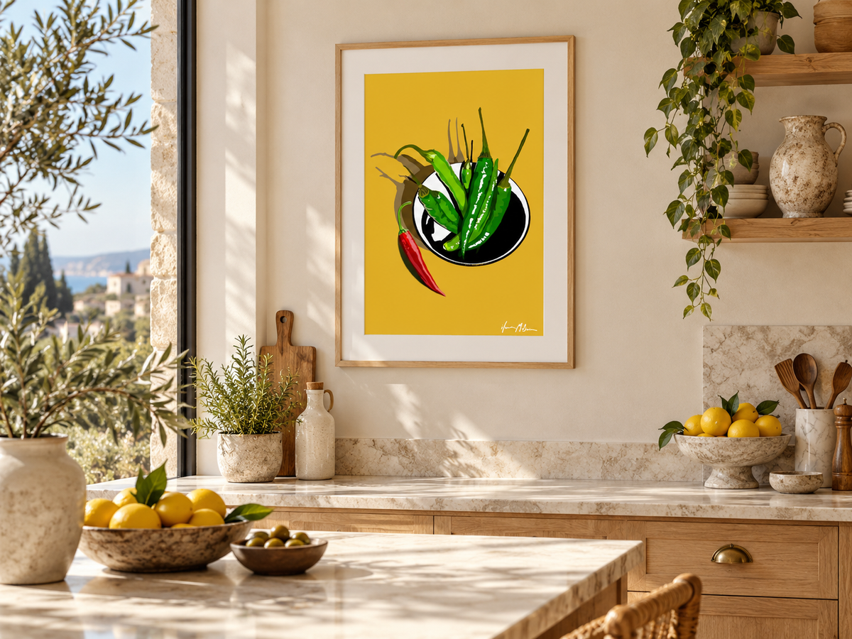 A Little Heat mustard chilli art print displayed in a sunlit Mediterranean-style dining room with natural timber furniture, woven chairs and warm neutral decor.
