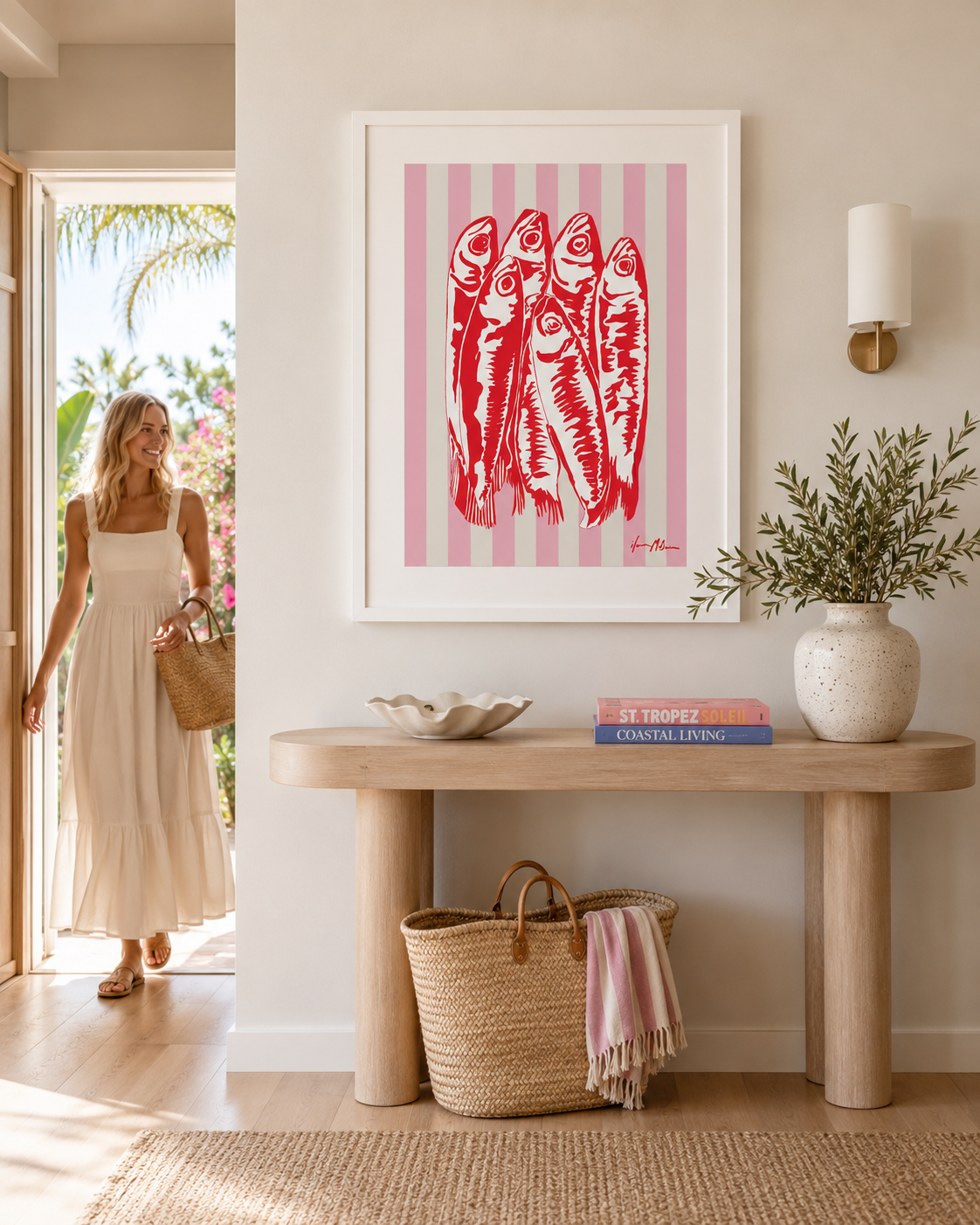 Modern coastal entry hall featuring a framed sardines pop art print by Ilana McBain displayed above a timber console table. Bright beach house interior with natural textures, soft pink accents, and contemporary coastal styling.