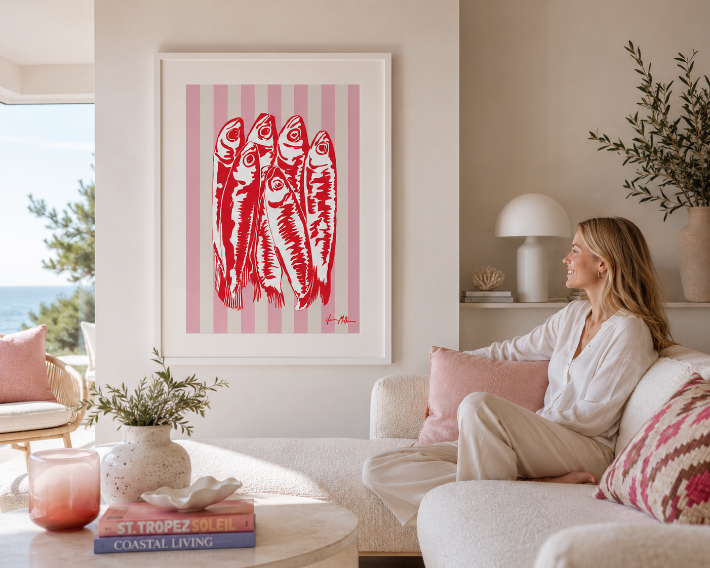 Modern coastal living room featuring a framed sardines pop art print by Ilana McBain with a white frame and wide white mat board. Bright contemporary interior with soft pink accents, ocean views, and relaxed beach house styling.