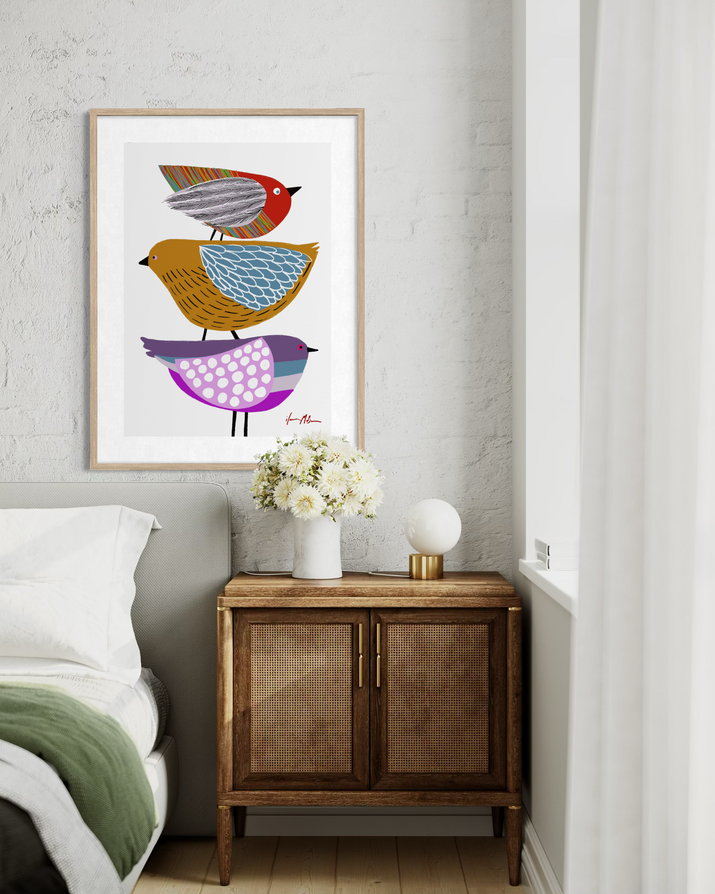 Contemporary colourful bird artwork by Australian artist Ilana McBain displayed as framed wall art above bedside cabinet in a modern bedroom interior.