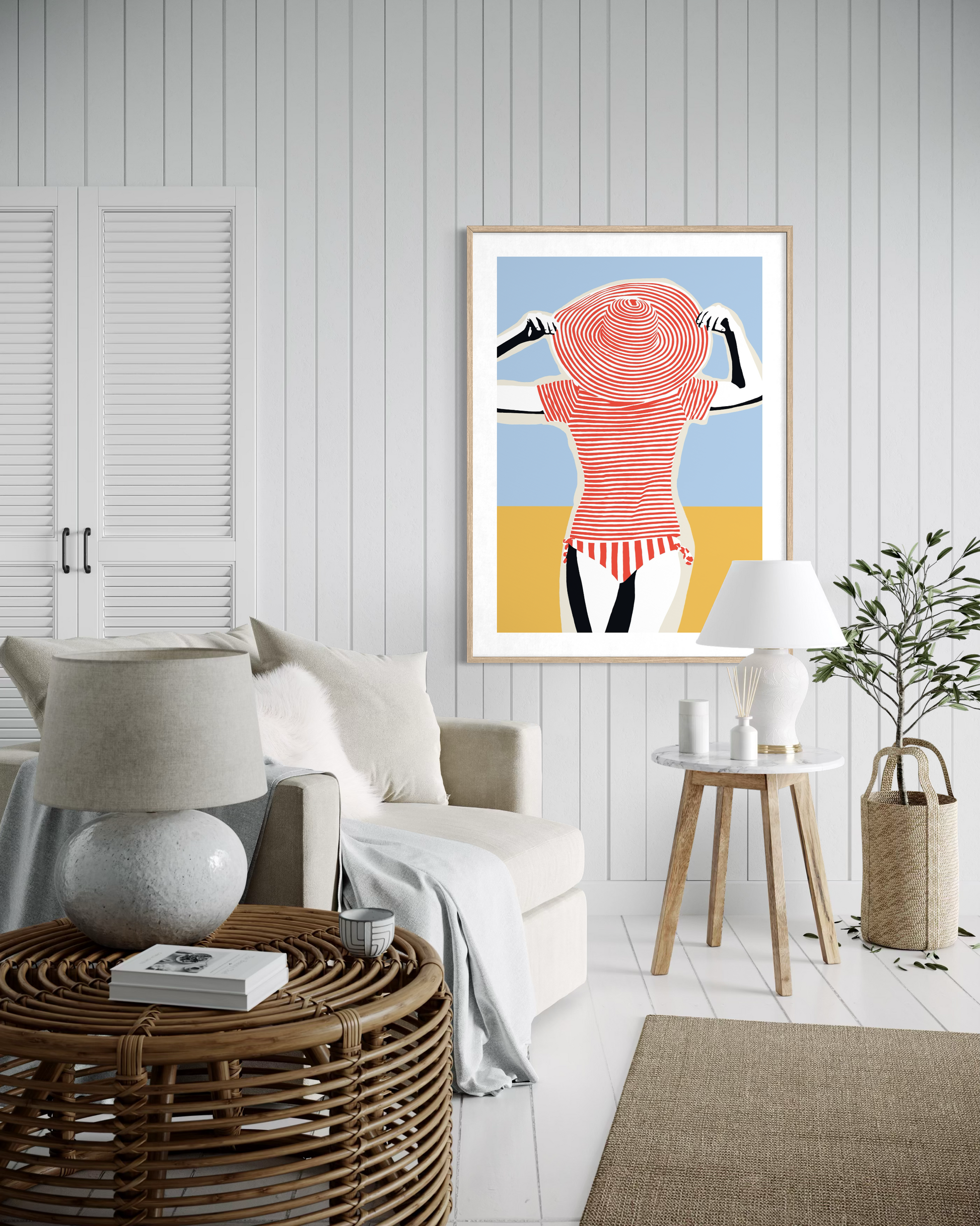 Retro beach pop art print by artist Ilana McBain showing a stylised woman in striped swimsuit and sun hat displayed in modern coastal living room interior.