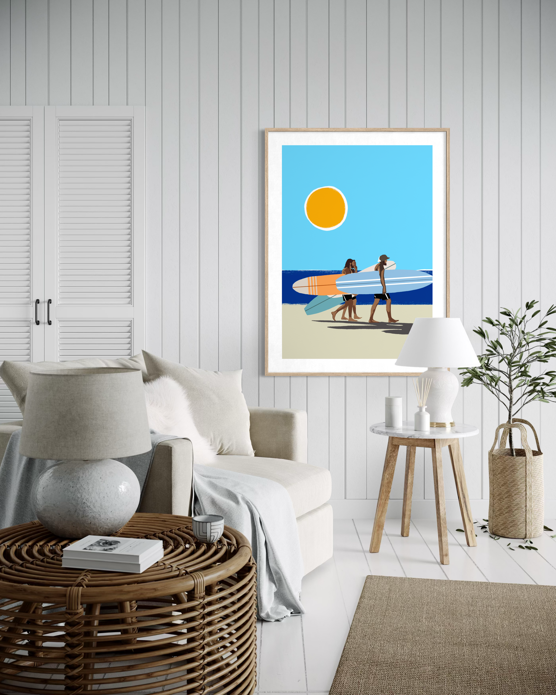 Modern coastal wall art featuring surfers carrying surfboards along a sunny beach by Australian artist Ilana McBain displayed above wooden bench in beach house interior.