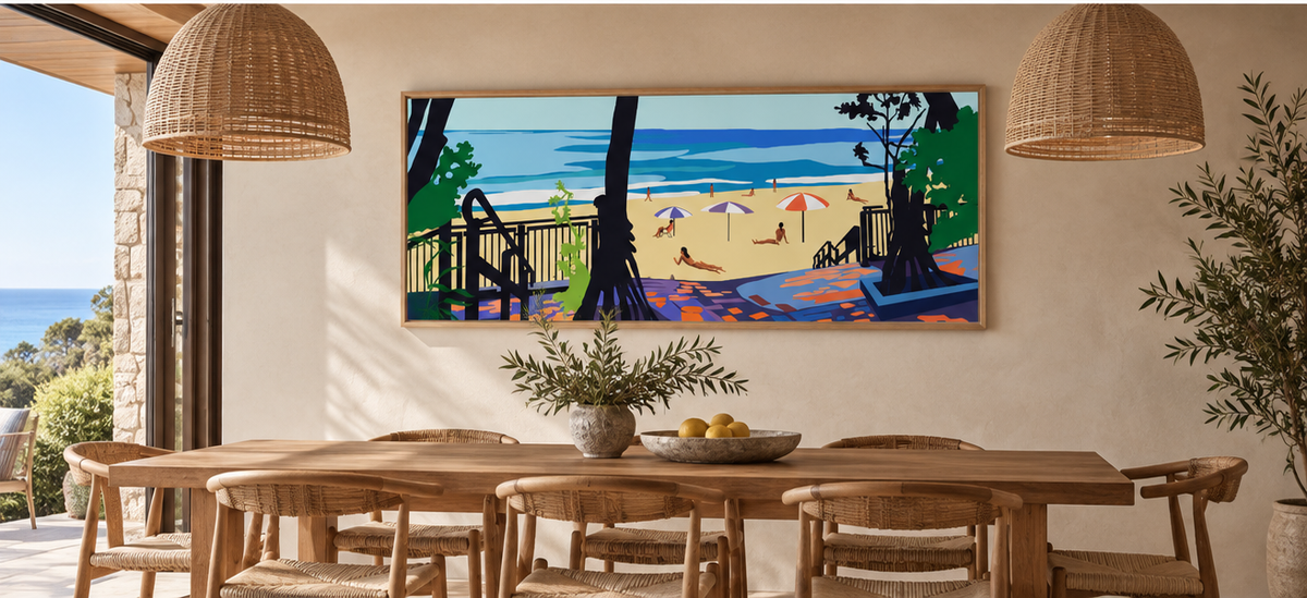 Little Cove by Ilana McBain displayed in a warm coastal dining room with timber furniture, woven chairs and natural light.