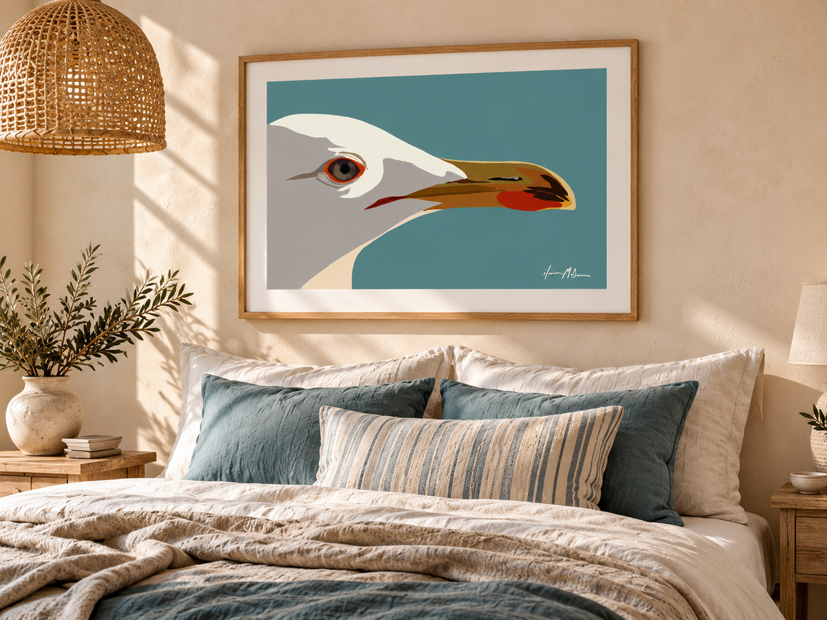 Side Eye contemporary seagull art print styled above a bed in a warm coastal bedroom with timber, linen and muted blue accents.