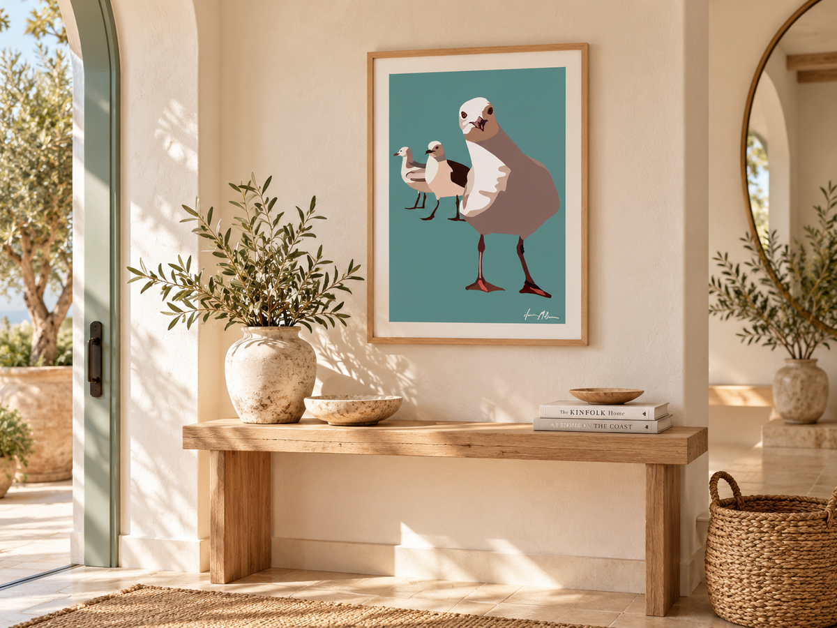 The Locals contemporary seagull art print by Ilana McBain displayed in a bright coastal entry hall with natural timber, woven textures and warm neutral styling.