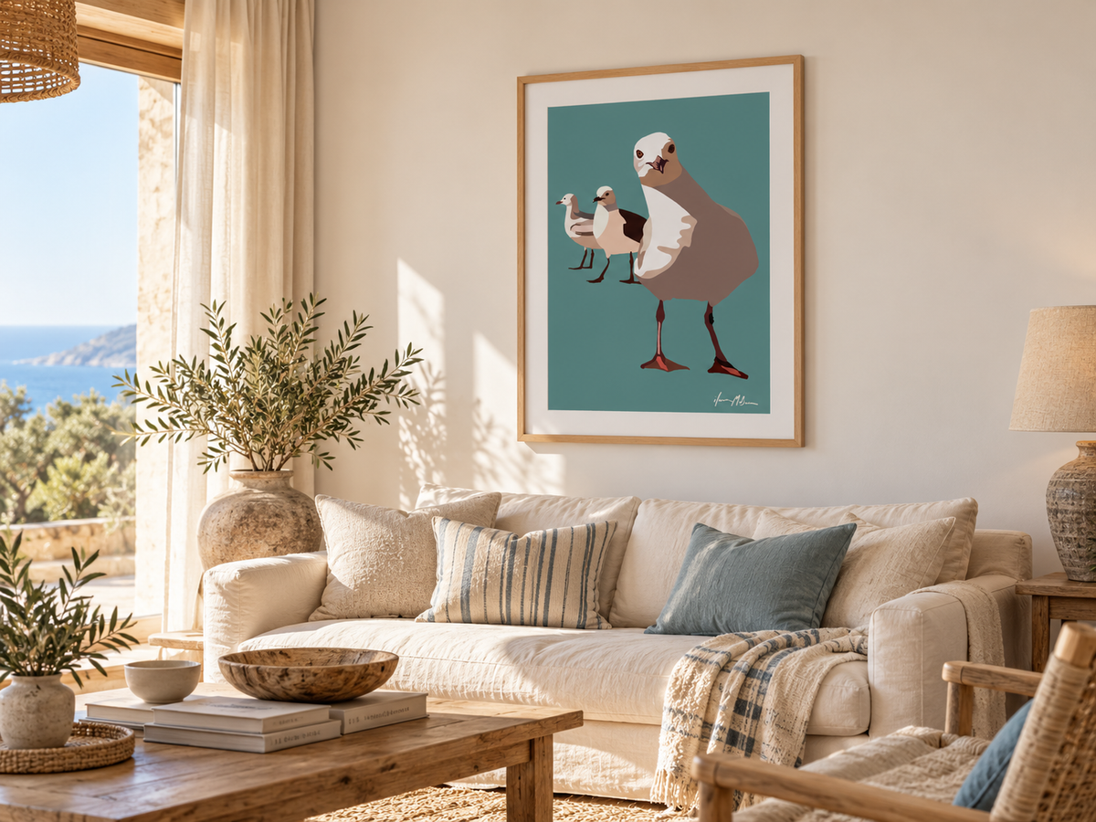 The Locals contemporary seagull art print by Ilana McBain displayed above a cream sofa in a sunlit coastal living room with natural timber and soft blue accents.